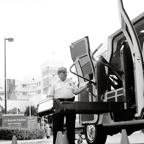 Black and white photo of a man operating a vehicle lift, showcasing accessibility.