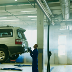 Mechanic conducts vehicle inspection in an automotive garage setting.
