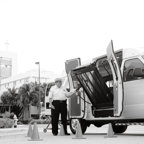 Transportation van with open accessibility lift in urban setting, black and white.