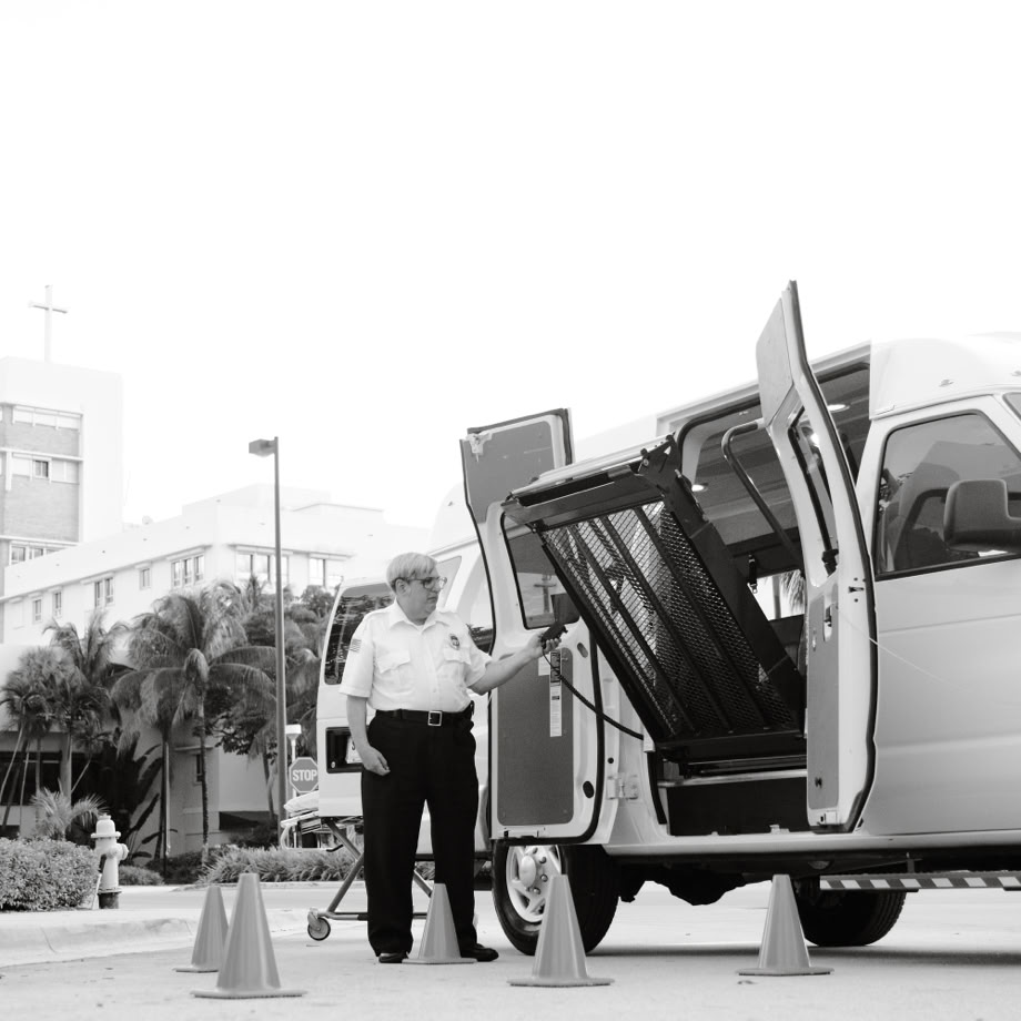 Transportation van with open accessibility lift in urban setting, black and white.