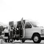 A black and white image depicting an accessible transport van with a lift, enhancing mobility for passengers with disabilities.
