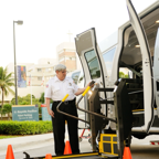 Safety officer demonstrating the use of a wheelchair lift in a van at a facility.